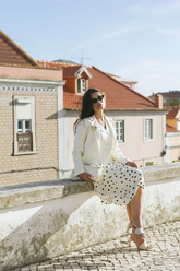 a lady in a white vest, a white blazer and a white skirt with polka dots